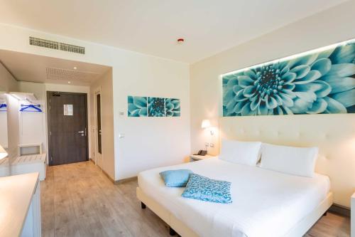 a bedroom with a white bed and a blue flower painting on the wall at ibis Styles Milano Est Settala in Settala
