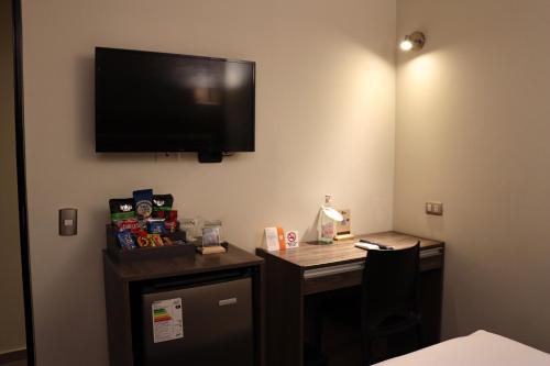 a room with a desk and a television on a wall at Rado Hotel - Santa María in Trujillo