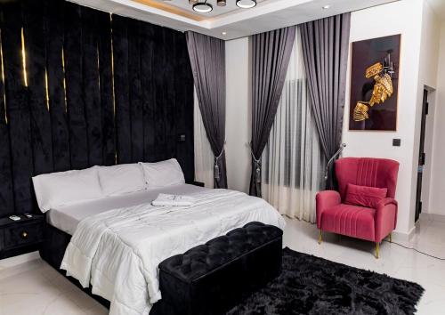 a bedroom with a large bed and a red chair at Luxury 4 Bedroom Ensuite - Lagos in Ikeja