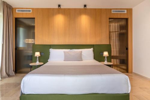 a bedroom with a large bed with two lamps at Essenza Relais Contemporaneo in Cisternino