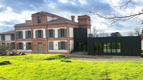 a large house on a grassy field in front at Domaine de Pousiniès in Saint-Étienne-de-Tulmont