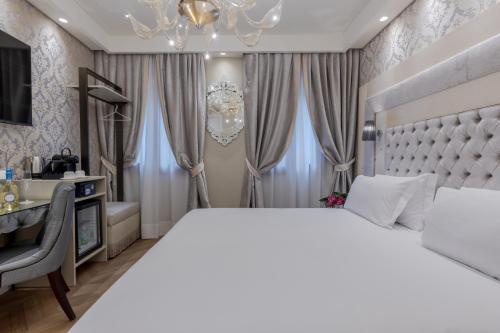 Un dormitorio con una gran cama blanca y un escritorio. en Cà dell'Arte Boutique, en Venecia