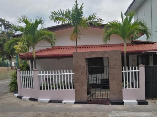 a house with palm trees and a white fence at MJM Villa in Colombo