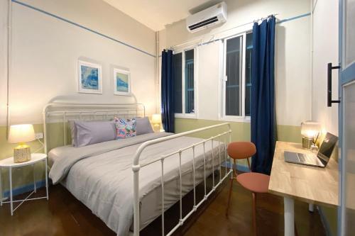 a bedroom with a bed and a desk and windows at BaanBaan - Cozy home 5pax, 5min BTS, Boat, old town explore in Bangkok