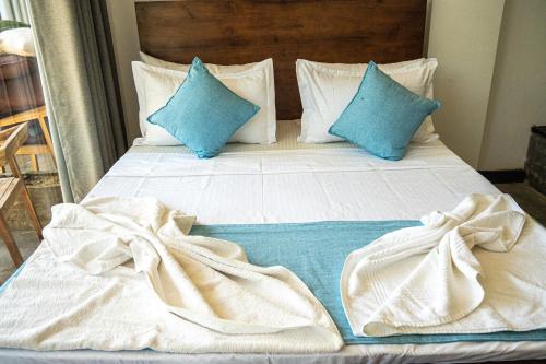 a bed with white sheets and blue pillows at Cocos in Midigama