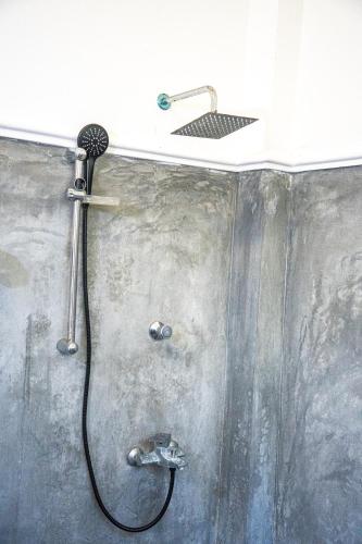 a shower with a hose attached to a wall at Cocos in Midigama