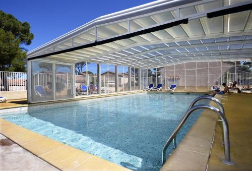 - une piscine avec un auvent avec des personnes assises dans l'établissement Maison, 8 places, 3 chambres, clim, piscine, tennis, à Calvisson