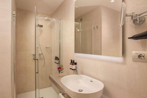 a white bathroom with a sink and a shower at NH Milano Corso Buenos Aires in Milan