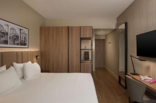 a bedroom with a large white bed and a television at NH Milano Corso Buenos Aires in Milan
