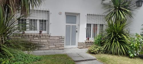 a white house with palm trees in front of a door at Apartamento calido in Mar del Plata