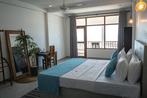 a bedroom with a large bed with a large window at Cocos in Midigama