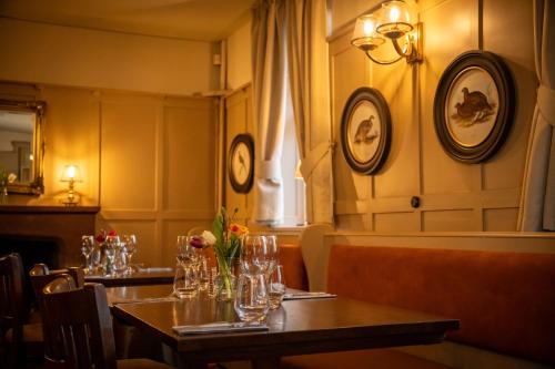 a restaurant with two tables with glasses and flowers at Anglers Arms in Alnwick