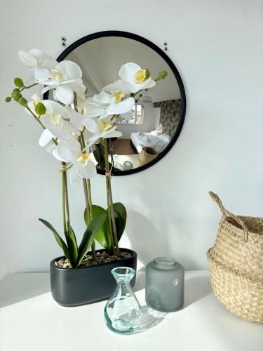 un miroir sur une table avec des fleurs blanches dans un vase dans l'établissement The Opal - 2bds in the city center, à Annecy
