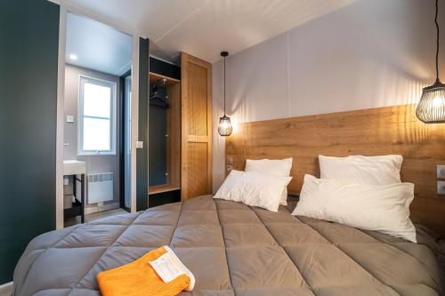 Cette chambre comprend un grand lit avec des oreillers blancs. dans l'établissement Camping maeva Respire Les Couleurs de la Coubre, aux Mathes