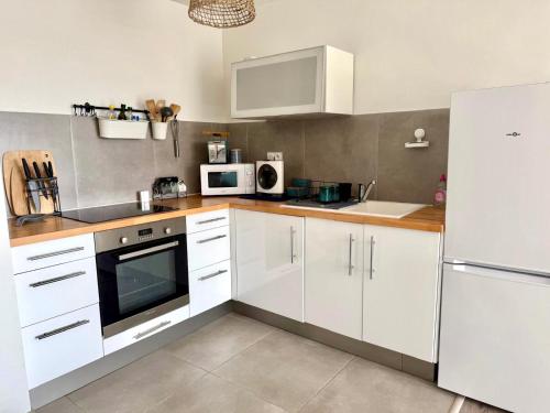 une cuisine avec des armoires blanches et un réfrigérateur blanc dans l'établissement La Casa Marina - Cozy apartment Frontignan Plage, à Frontignan