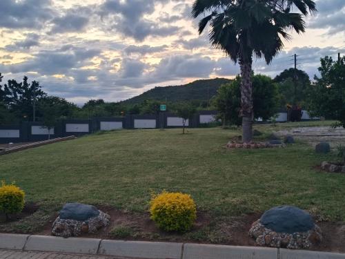 a park with a palm tree and a grass field at Sagwadi Hotel in Hazyview