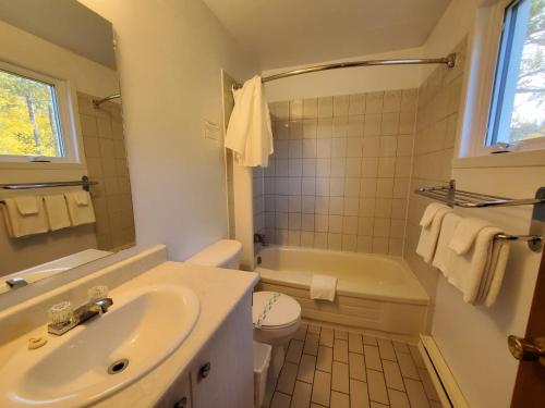 a white bathroom with a sink and a toilet at Hotel - Motel Georges in Tadoussac