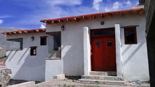 ein kleines Haus mit einer roten Tür an der Seite in der Unterkunft Cabañas Mallma in Tilcara
