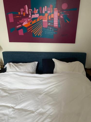 - une chambre avec un lit blanc et un tableau au-dessus dans l'établissement Franca View Defense, à Puteaux