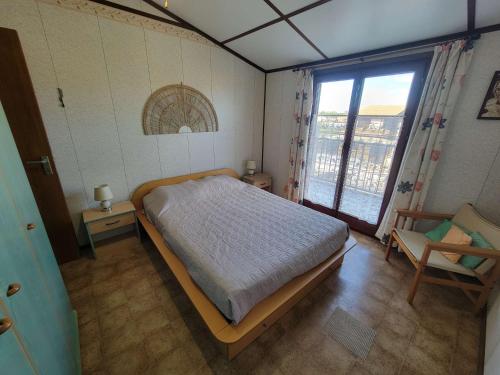 une chambre avec un lit, une fenêtre et une chaise dans l'établissement Belle villa d'angle spacieuse climatisée, dans domaine PORTES DU SOLEIL, 3 chambres, 6 couchages, wifi, 400m de la mer LRPDSA6, à Portiragnes