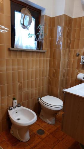 a bathroom with a toilet and a sink and a window at Villa Damiano in Tarquinia