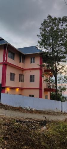 a pink building with a tree in front of it at Dam Valley Home Stay Resort in Parambikolam