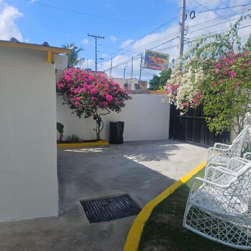 a patio with two white chairs and pink flowers at Villa del sol in Infiernito