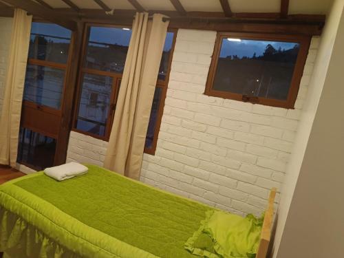 a bedroom with a green bed and a window at Chuza Longa Home in Guamote