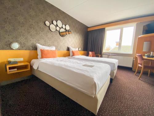 a hotel room with a large bed and a table at Hotel Aalsmeer in Aalsmeer