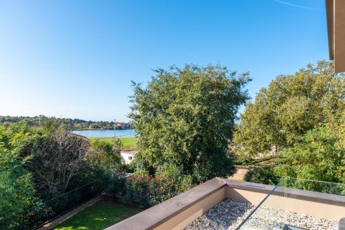 a balcony with a view of a river and trees at Quercus Village Penthouse with jacuzzi in Novigrad Istria