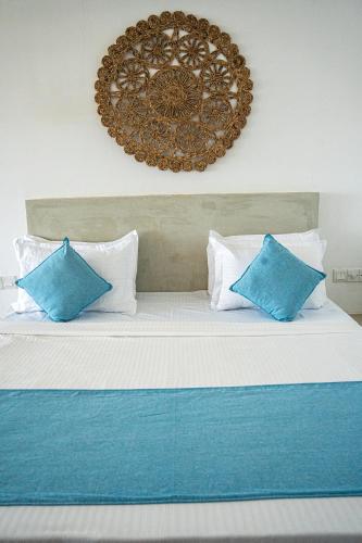 a bed with blue and white pillows on it at Cocos in Midigama