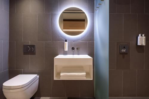 a bathroom with a toilet and a sink and a mirror at Zedwell Hotel Piccadilly Circus in London