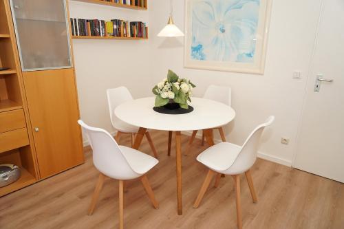 a white table with white chairs and a vase of flowers at Ferienwohnung zur Hafenseite _ 200 in Damp