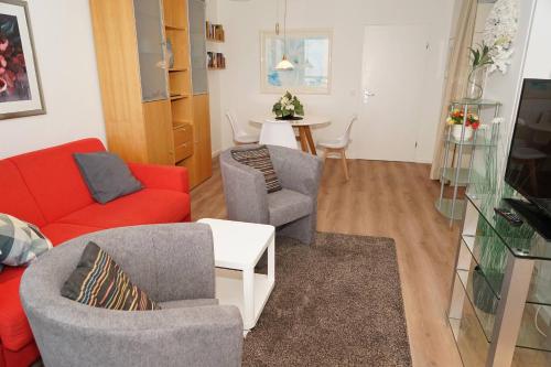 a living room with a red couch and chairs at Ferienwohnung zur Hafenseite _ 200 in Damp