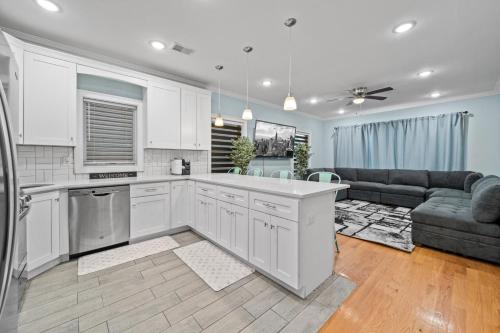 a kitchen and living room with white cabinets and a couch at Skyline Haven Luxe NYC Escape in Jersey City