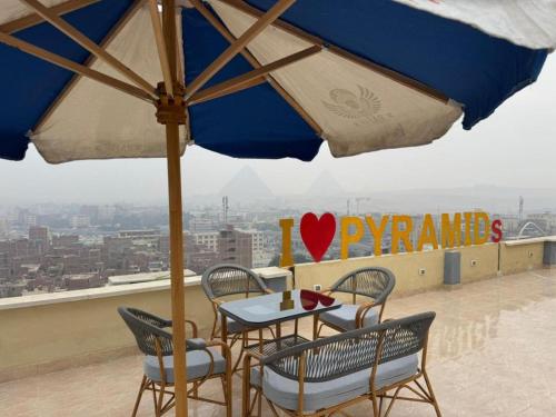 a table and chairs with an umbrella on a roof at Pyramids Rafif Hotel in Cairo