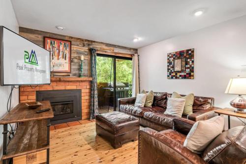a living room with a couch and a fireplace at Modern Mountain Riverfront Condo, Walk to Lift in Avon
