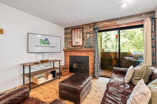 a living room with a couch and a fireplace at Modern Mountain Riverfront Condo, Walk to Lift in Avon