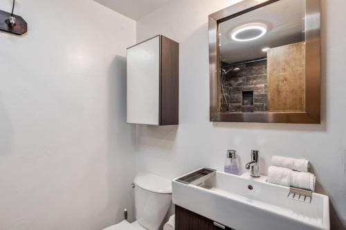 a bathroom with a sink and a toilet and a mirror at Modern Mountain Riverfront Condo, Walk to Lift in Avon