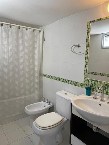 a white bathroom with a toilet and a sink at Freire Suites in Buenos Aires