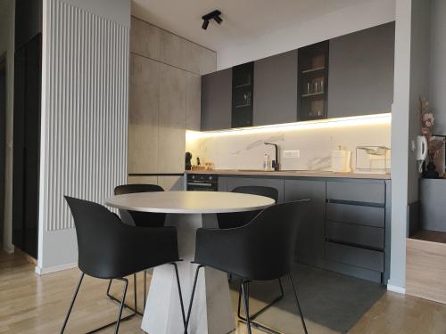 a kitchen with a white table and black chairs at BS Apartment in Skopje