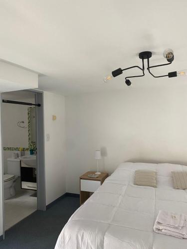 a bedroom with a white bed with a light on the ceiling at Freire Suites in Buenos Aires