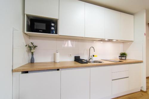 a white kitchen with a sink and a microwave at Flexible SelfCheckIns 71 - Zagreb - New - Center - 50m from the Main Square in Zagreb
