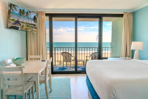 a hotel room with a bed and a table and a balcony at Direct Oceanfront 1 Bedroom Suite! Schooner At Compass Cove 335- Sleeps 4! in Myrtle Beach