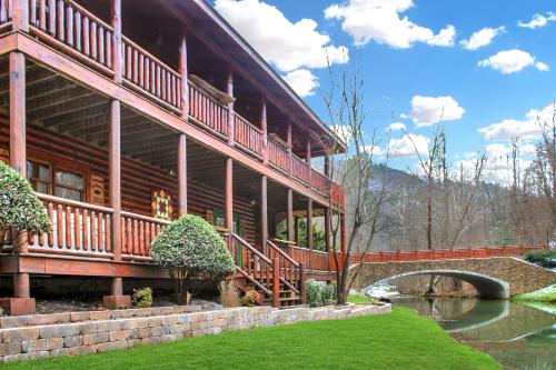 a large wooden building with a bridge next to a river at Creekside Lodge in Sevierville