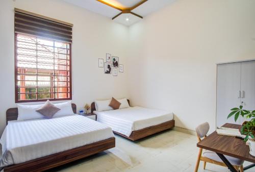 a bedroom with two beds and a desk and a window at House of Pi Pleiku in Pleiku