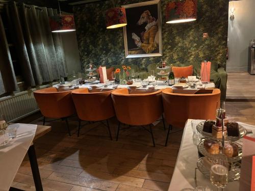 a dining room with a long table with orange chairs at Tottington Manor Hotel in Henfield