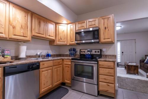 a kitchen with wooden cabinets and stainless steel appliances at Cozy Relaxing Retreat Near Downtown SLC in Salt Lake City
