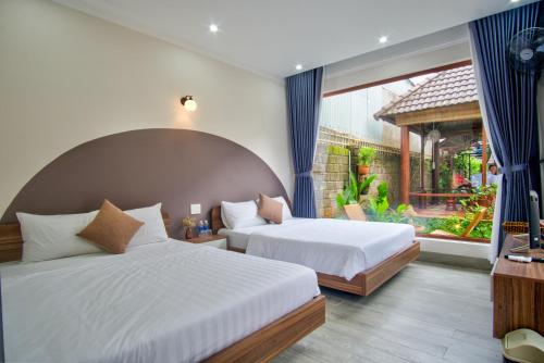 a bedroom with two beds and a large window at House of Pi Pleiku in Pleiku