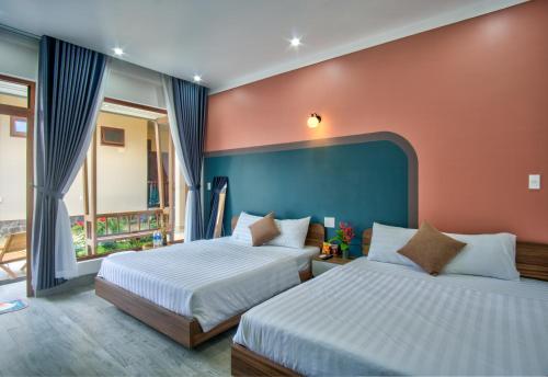a bedroom with two beds and a blue wall at House of Pi Pleiku in Pleiku